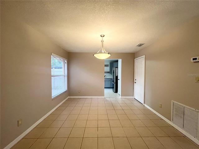 unfurnished room featuring light tile patterned flooring and a textured ceiling