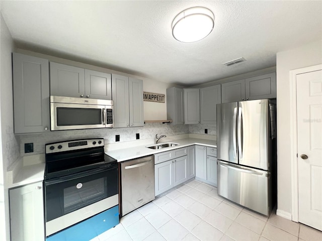 kitchen featuring gray cabinets, light tile patterned floors, sink, and appliances with stainless steel finishes