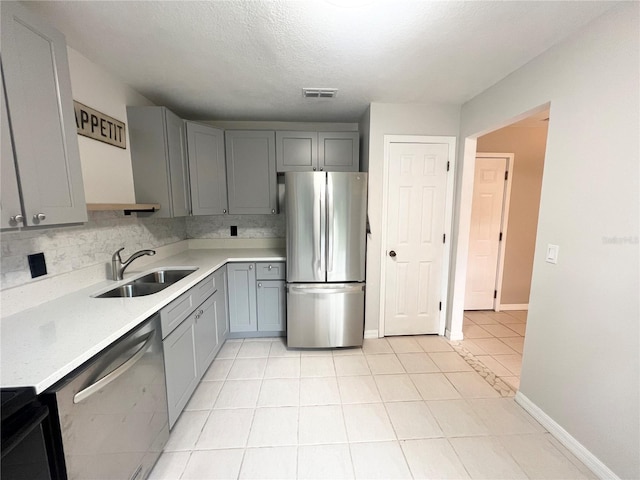 kitchen featuring gray cabinets, sink, light tile patterned flooring, and stainless steel appliances