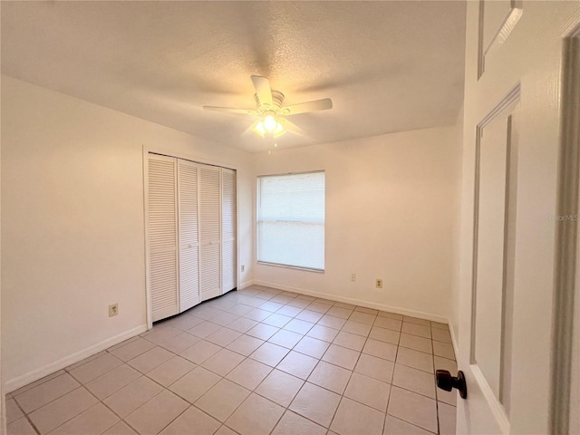 unfurnished bedroom featuring ceiling fan, a closet, light tile patterned flooring, and a textured ceiling