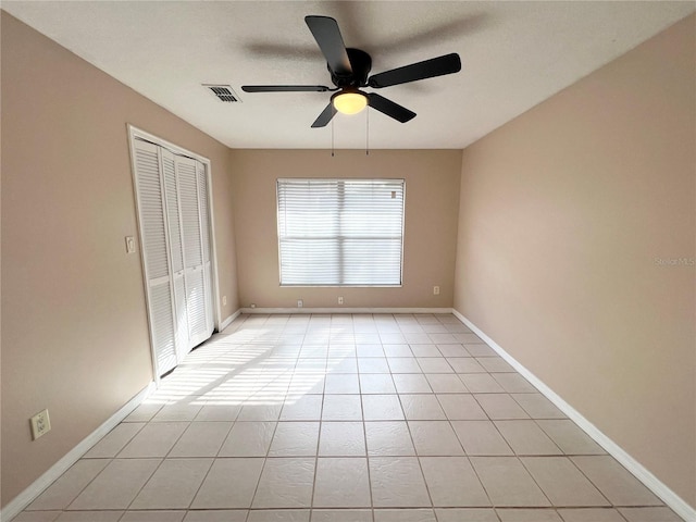 tiled spare room with ceiling fan