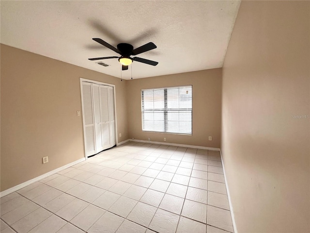 unfurnished bedroom with ceiling fan, light tile patterned floors, a textured ceiling, and a closet