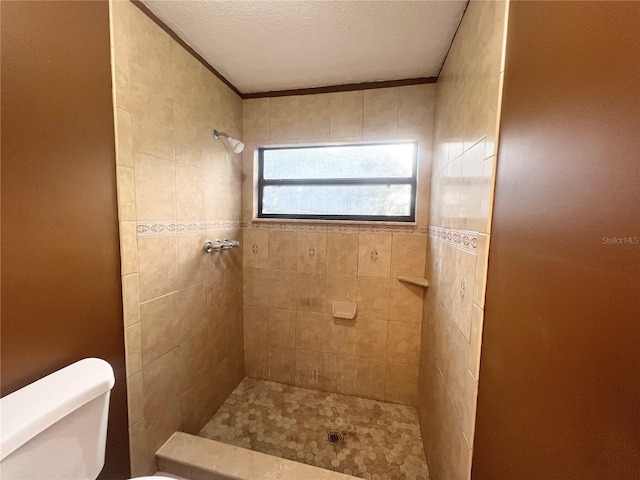 bathroom featuring tiled shower, a textured ceiling, and toilet