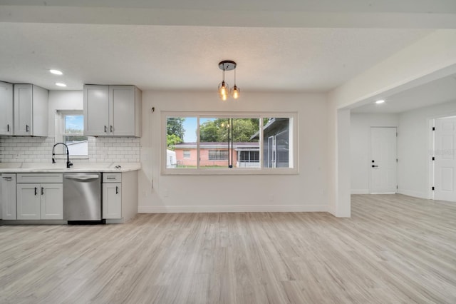 kitchen with sink, decorative light fixtures, dishwasher, light hardwood / wood-style floors, and decorative backsplash