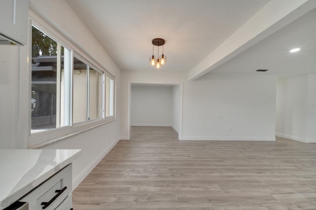 unfurnished dining area with a chandelier and light hardwood / wood-style floors