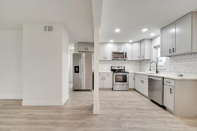 kitchen featuring sink, decorative backsplash, light hardwood / wood-style flooring, and appliances with stainless steel finishes