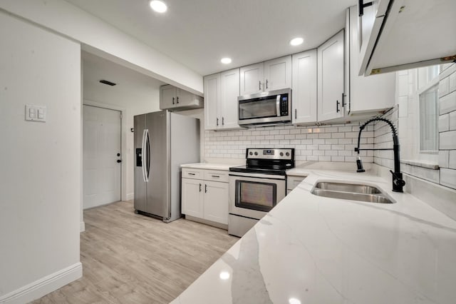 kitchen featuring stainless steel appliances, light stone countertops, sink, and white cabinets