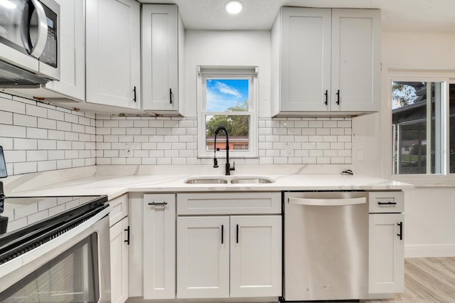 kitchen with stainless steel appliances, light stone countertops, sink, and decorative backsplash