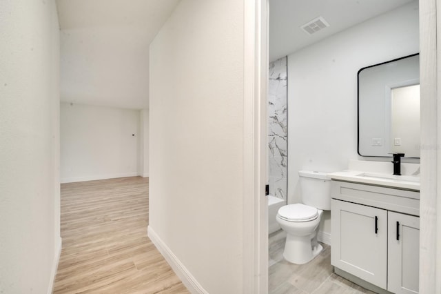 full bathroom featuring hardwood / wood-style flooring, vanity, shower / washtub combination, and toilet