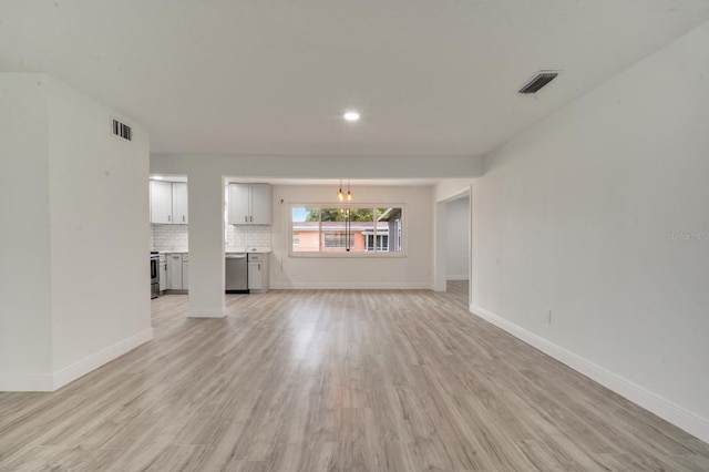 unfurnished living room featuring a chandelier and light hardwood / wood-style floors