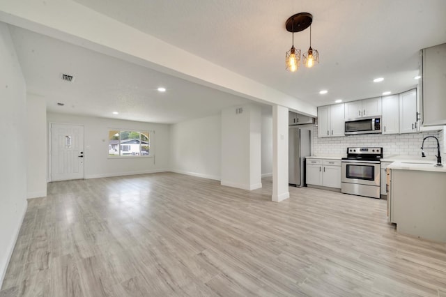 kitchen featuring tasteful backsplash, sink, light hardwood / wood-style flooring, and appliances with stainless steel finishes