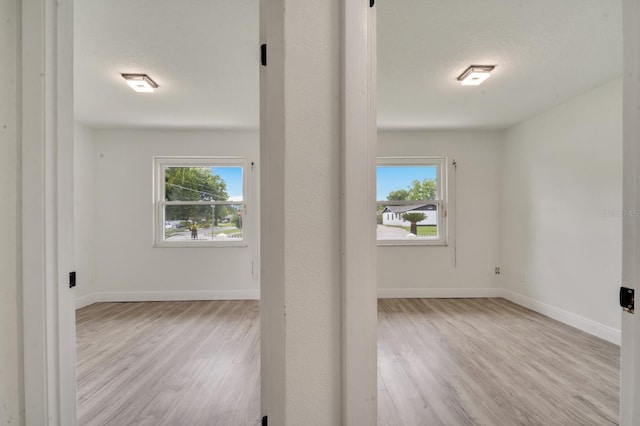 unfurnished room with a textured ceiling and light wood-type flooring