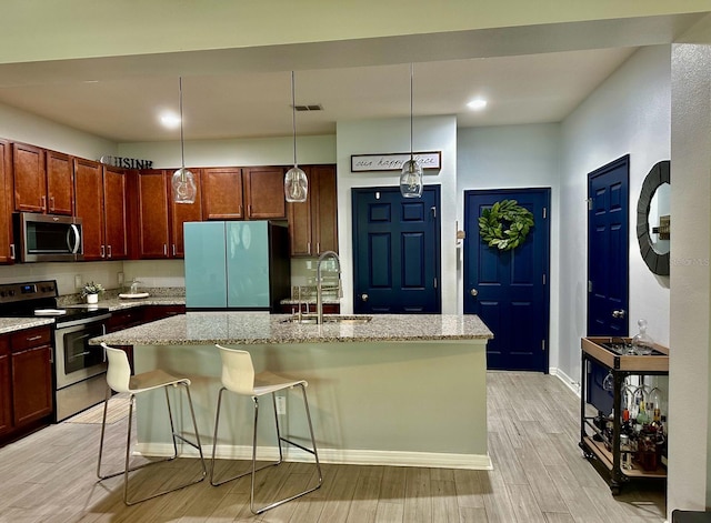 kitchen featuring a breakfast bar area, a center island with sink, light hardwood / wood-style flooring, stainless steel appliances, and sink