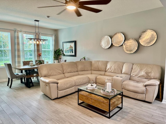 living room with a textured ceiling, light hardwood / wood-style flooring, and ceiling fan with notable chandelier