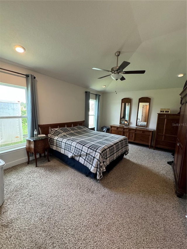 carpeted bedroom featuring ceiling fan and multiple windows