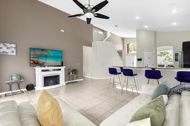 tiled living room with ceiling fan and a towering ceiling