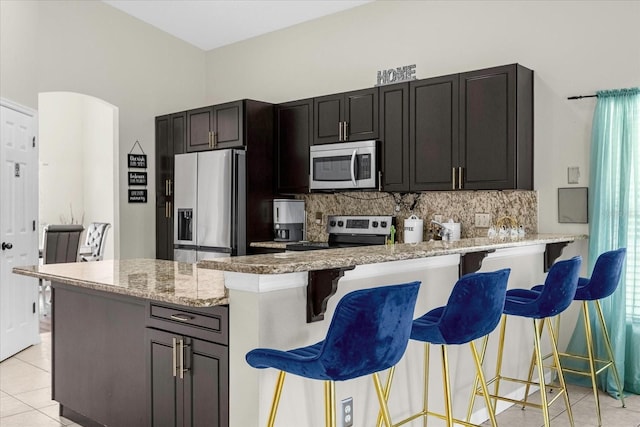 kitchen with tasteful backsplash, kitchen peninsula, a breakfast bar, and appliances with stainless steel finishes