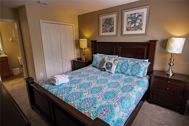 carpeted bedroom featuring a closet and ensuite bath