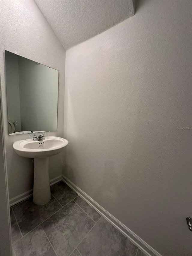 bathroom featuring tile patterned flooring, a textured ceiling, and vaulted ceiling