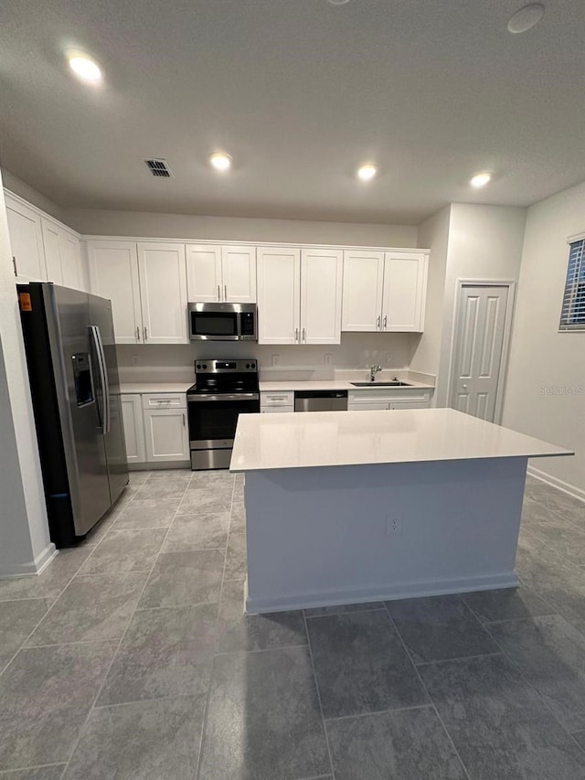 kitchen with white cabinets, a kitchen island, sink, and stainless steel appliances