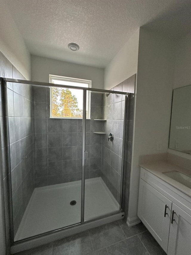 bathroom featuring a textured ceiling, vanity, tile patterned floors, and an enclosed shower