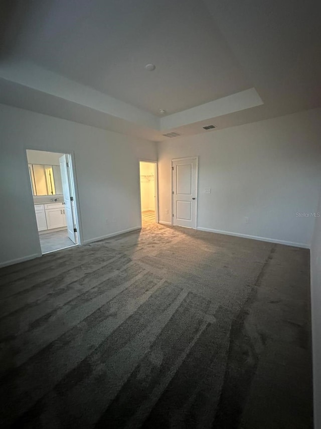 carpeted spare room featuring a tray ceiling