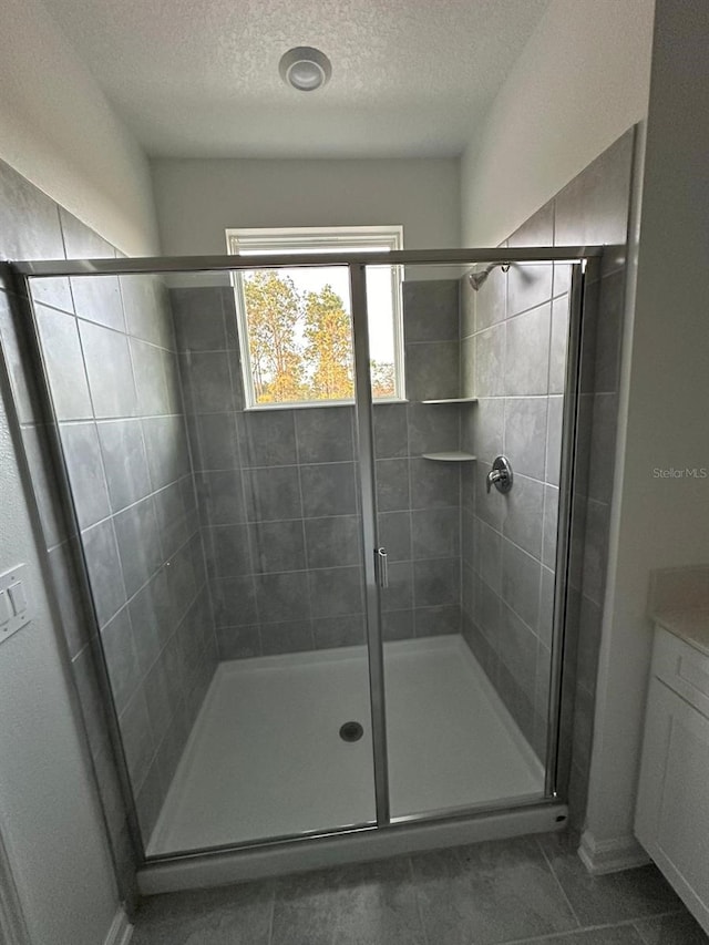 bathroom with vanity, a shower with door, and a textured ceiling