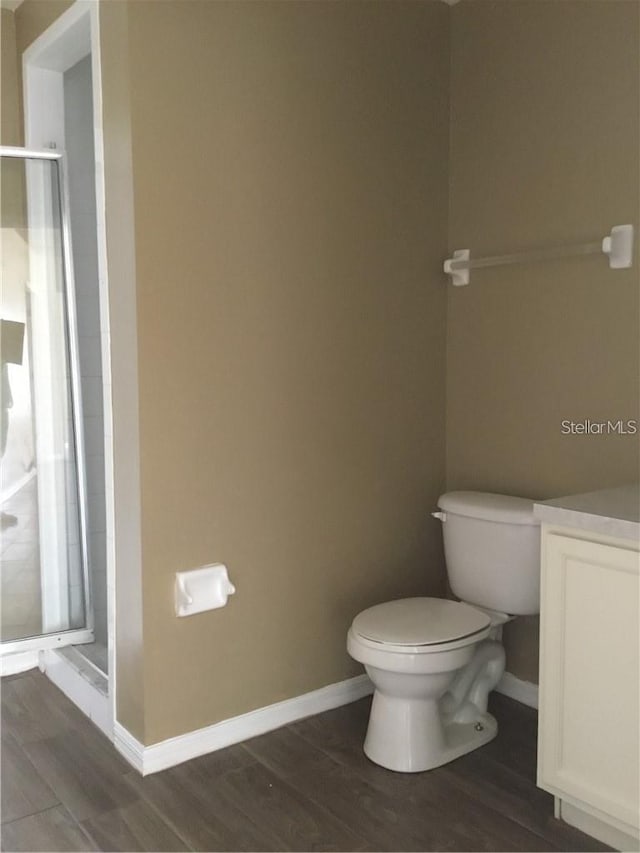 bathroom with wood-type flooring, toilet, a shower with door, and vanity