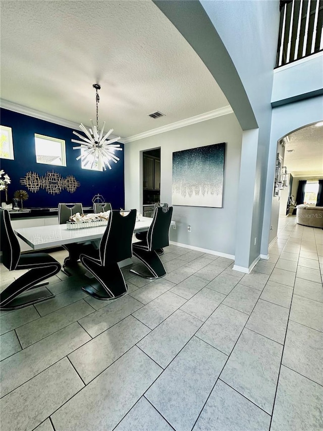 tiled dining room with ornamental molding, a textured ceiling, and a notable chandelier