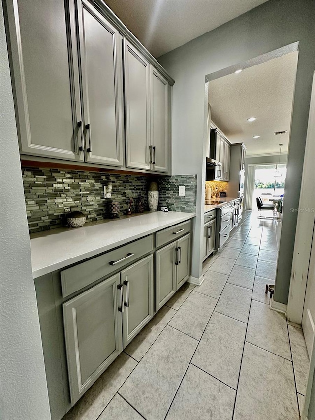 kitchen featuring light tile patterned floors, decorative backsplash, gray cabinets, and a textured ceiling