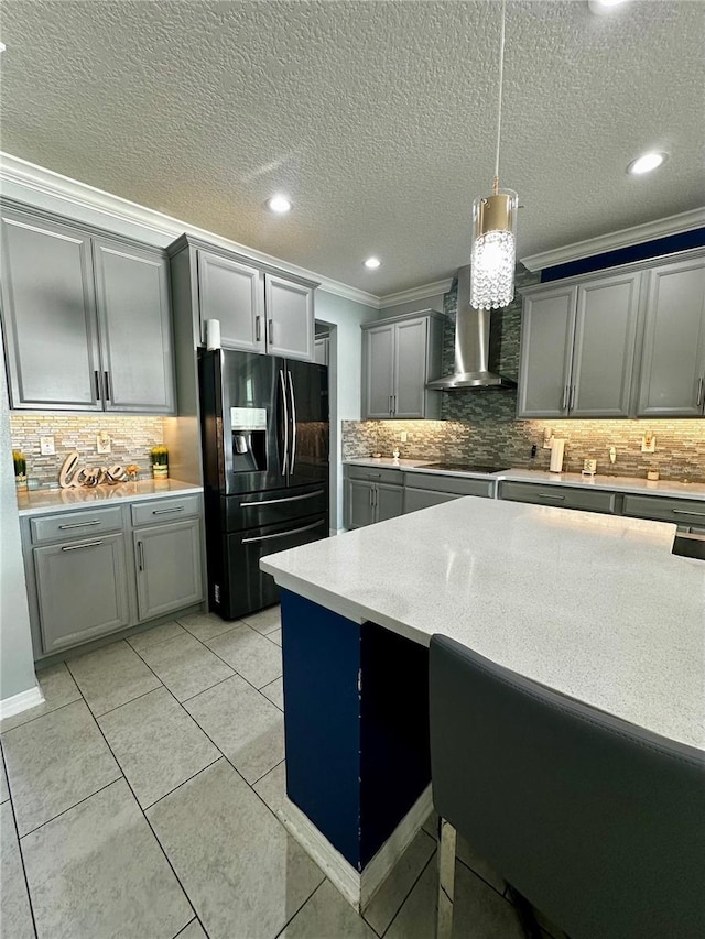 kitchen with gray cabinetry, hanging light fixtures, black appliances, and wall chimney exhaust hood