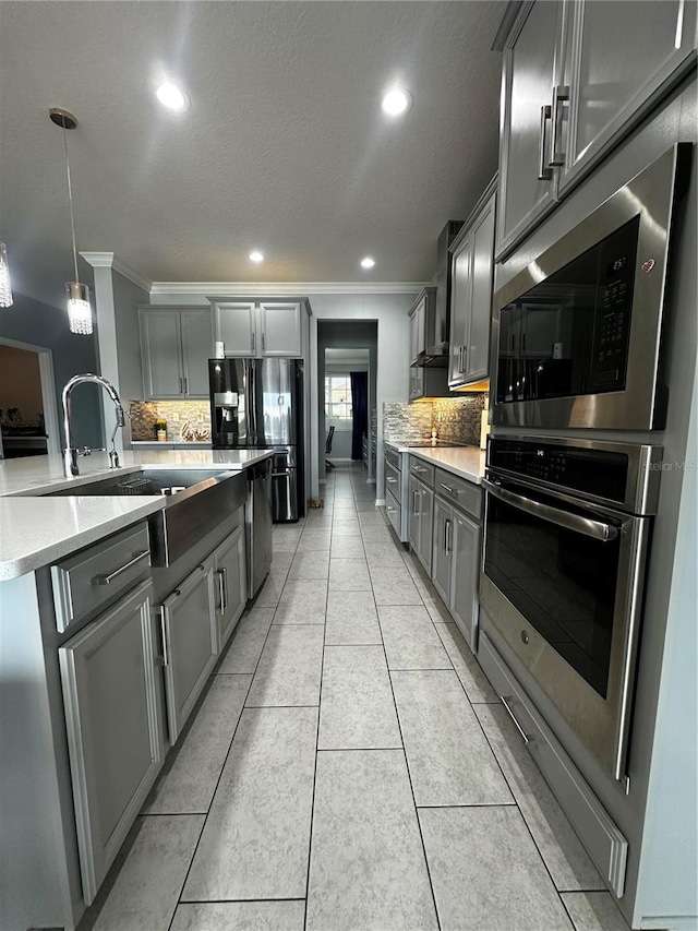 kitchen with pendant lighting, gray cabinets, sink, and decorative backsplash