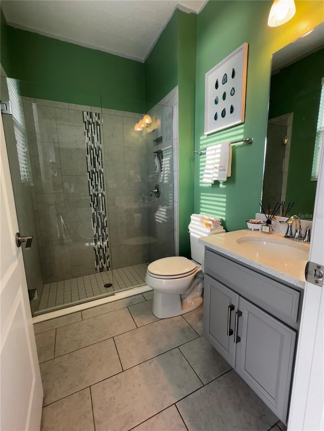 bathroom with tile patterned flooring, vanity, a shower with door, and toilet