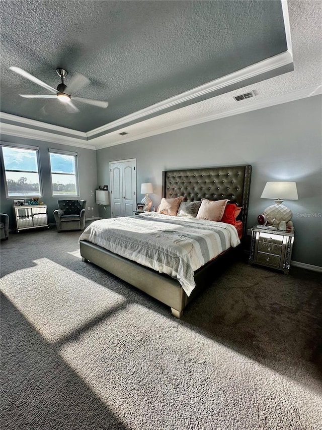 carpeted bedroom featuring crown molding, ceiling fan, a tray ceiling, and a textured ceiling