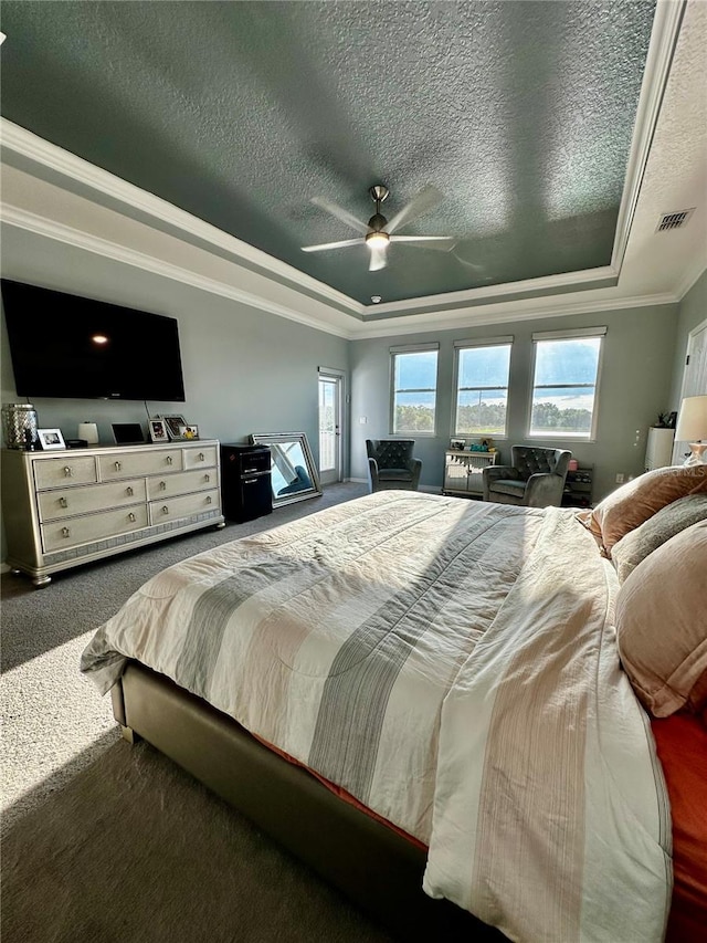 carpeted bedroom featuring ornamental molding, a textured ceiling, ceiling fan, and a tray ceiling