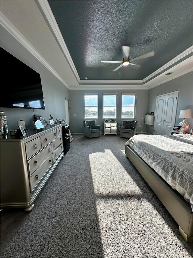 bedroom featuring a textured ceiling, ornamental molding, a raised ceiling, and ceiling fan