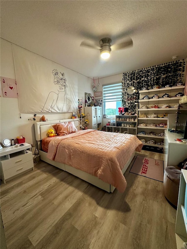 bedroom with ceiling fan, wood-type flooring, and a textured ceiling