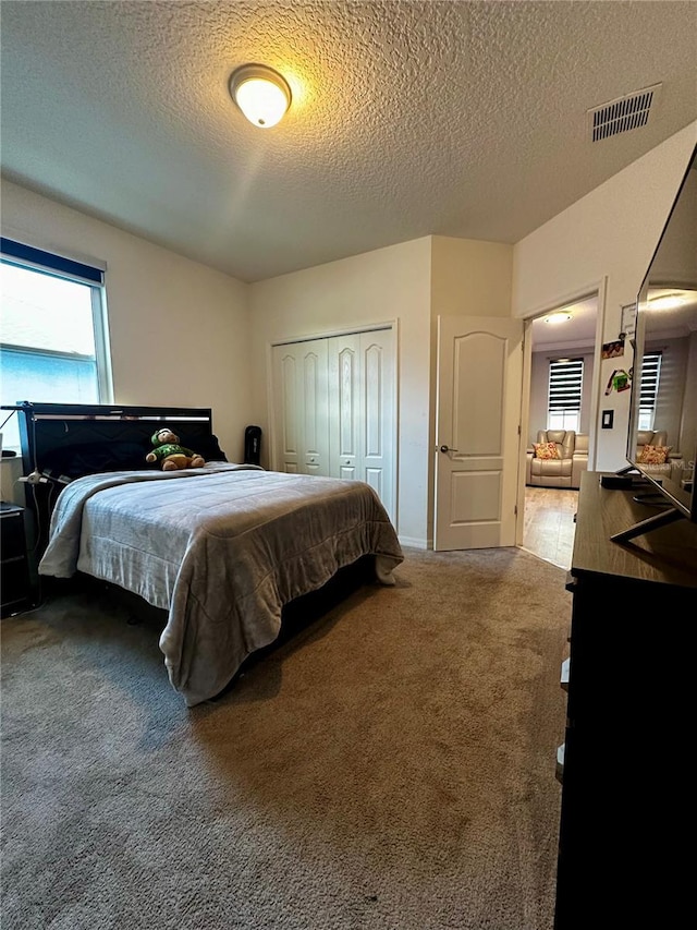 carpeted bedroom featuring a closet and a textured ceiling