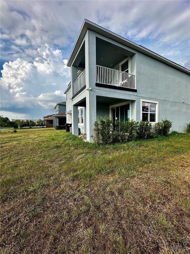 rear view of property with a balcony and a lawn