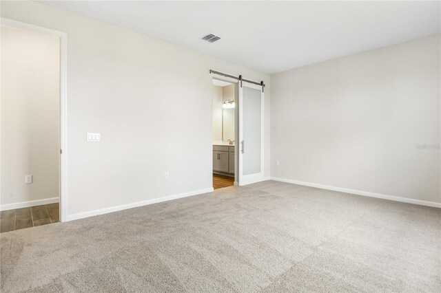 spare room featuring a barn door and carpet floors