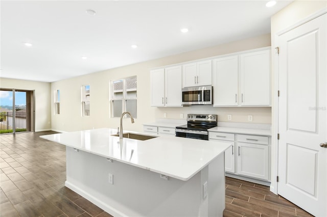 kitchen featuring appliances with stainless steel finishes, sink, white cabinetry, and an island with sink