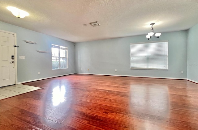 foyer with a textured ceiling, wood-type flooring, and a notable chandelier