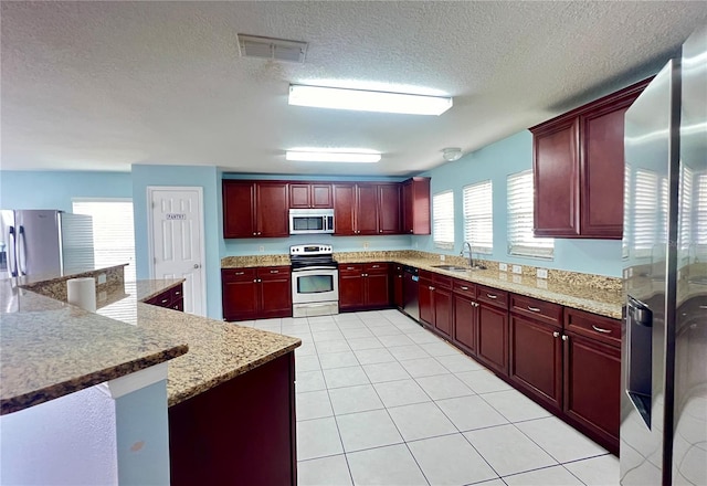 kitchen featuring a textured ceiling, appliances with stainless steel finishes, light tile patterned flooring, and sink