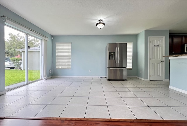 unfurnished living room with a textured ceiling and light tile patterned floors