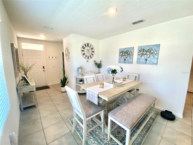 dining space featuring light tile patterned floors and a textured ceiling