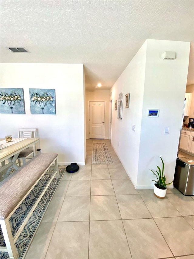 hall featuring light tile patterned floors and a textured ceiling