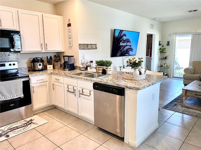 kitchen with white cabinets, light tile patterned floors, kitchen peninsula, and appliances with stainless steel finishes