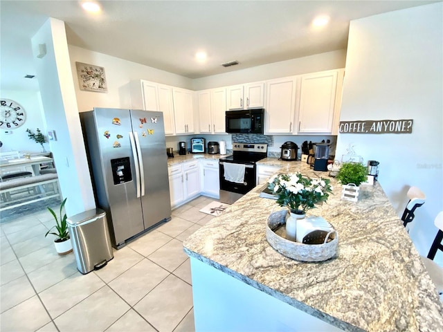 kitchen with white cabinets, light stone counters, kitchen peninsula, and appliances with stainless steel finishes