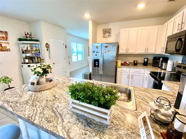 kitchen with white cabinets, light stone countertops, light tile patterned floors, and stainless steel appliances