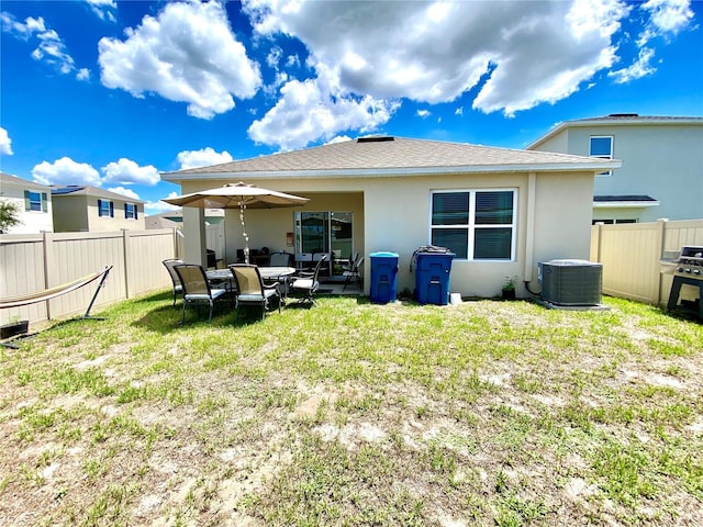 rear view of property featuring a yard and central AC unit